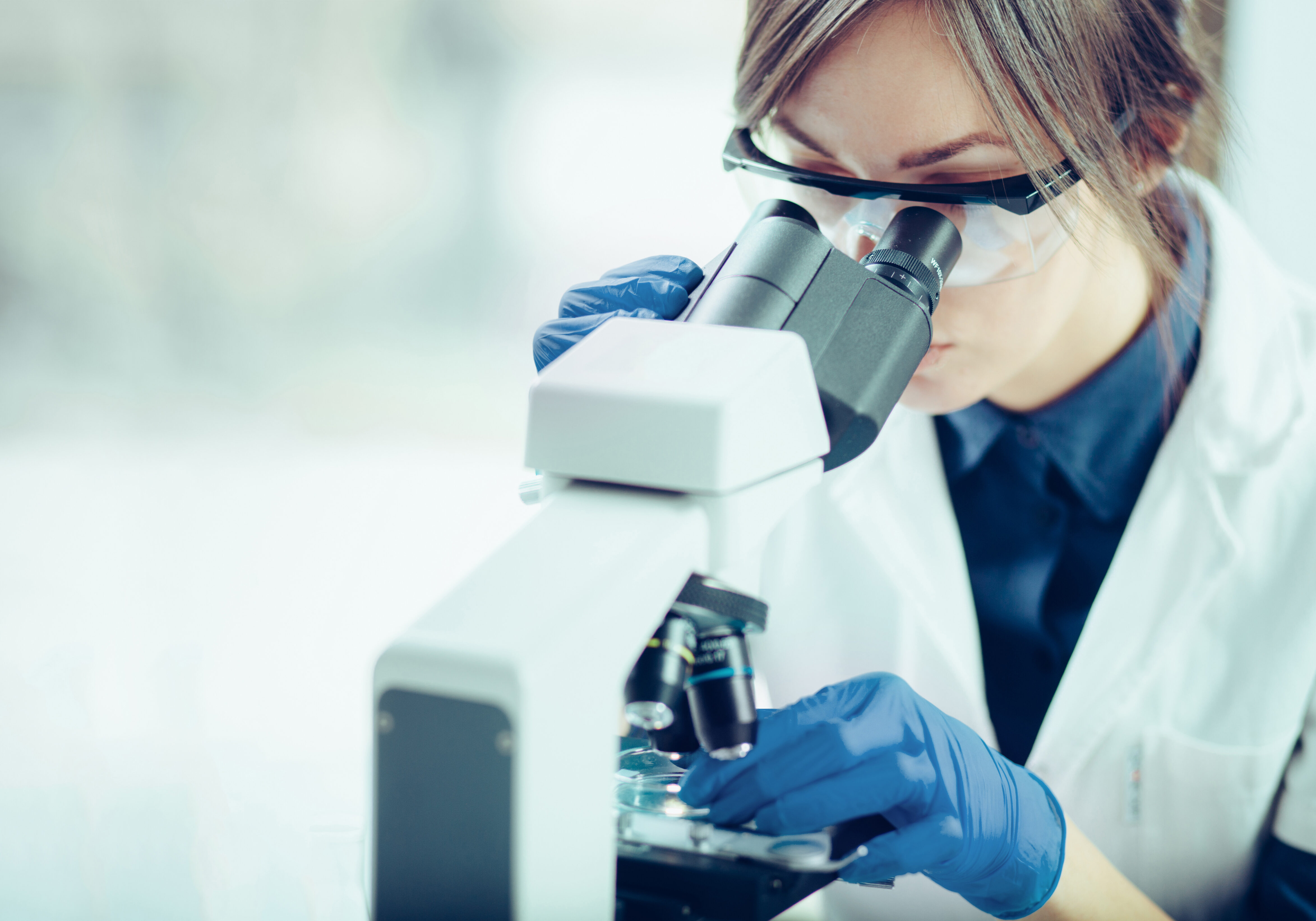 Medical professional looking at a slide through a microscope.